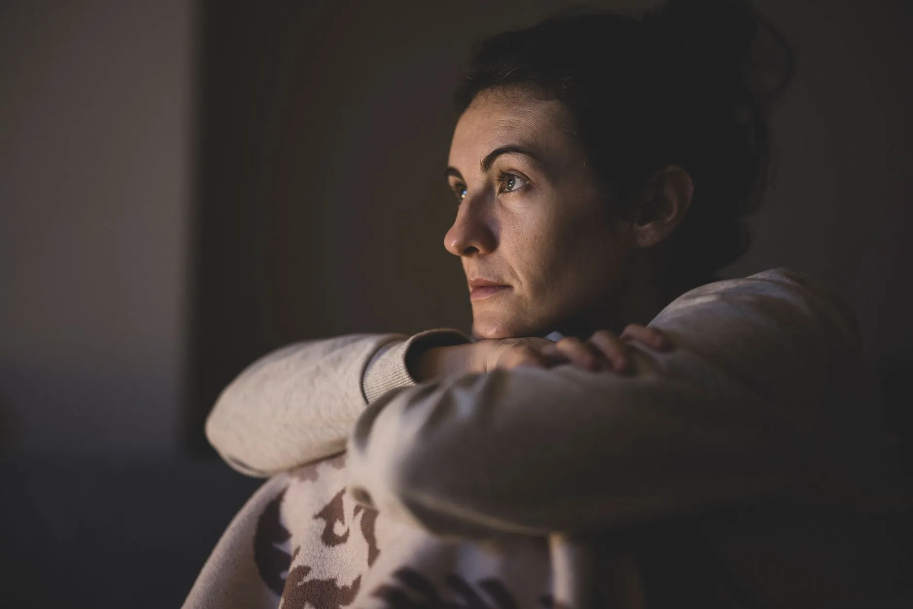 A woman sitting quietly in a dimly lit room