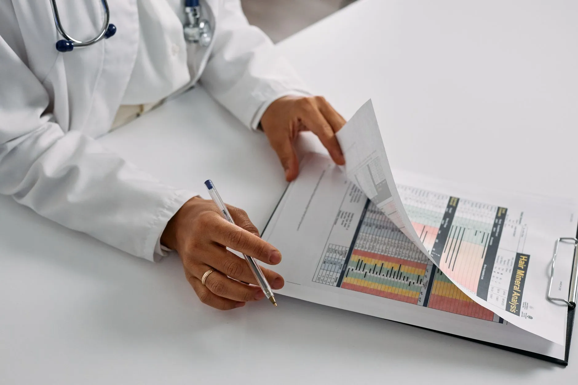 A clinician reading through printed pathology reports at a desk