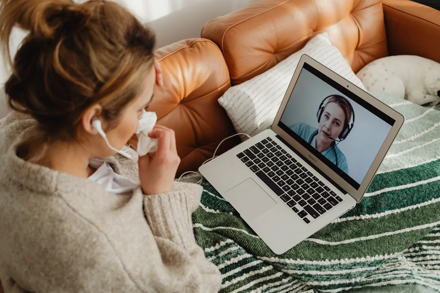 A woman speaking with a practitioner by video consultation from her sofa