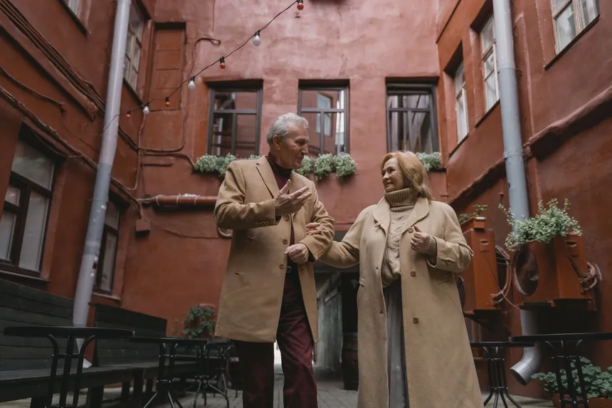 An older couple walking hand in hand along a city street