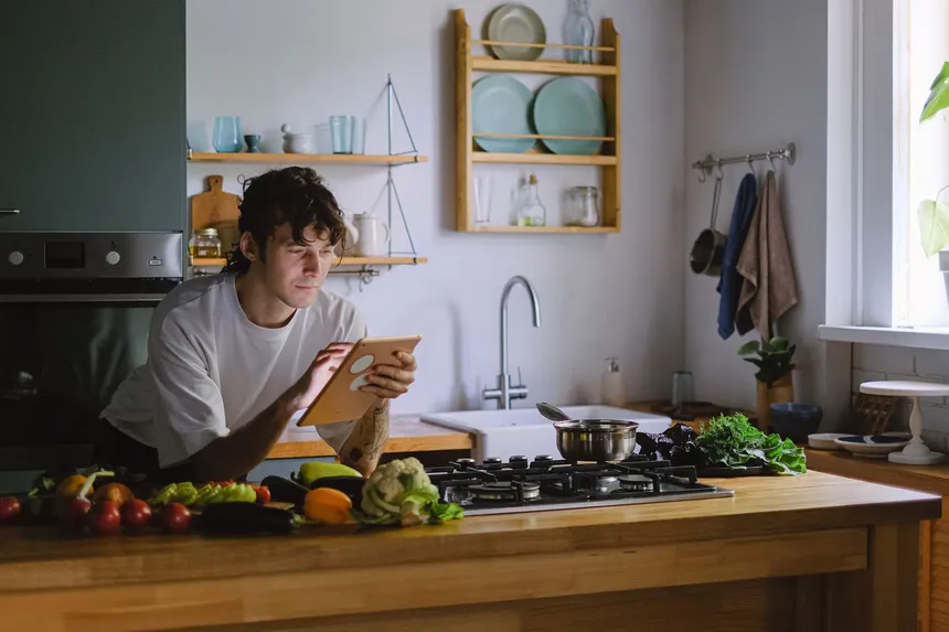 A man preparing fresh vegetables in a sunlit kitchen