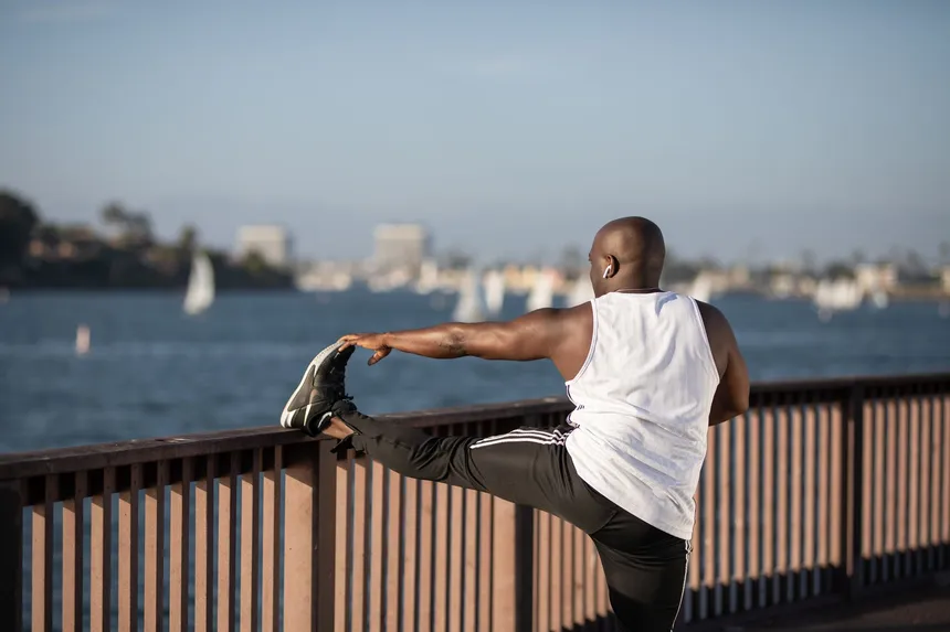 A man stretching by the water after a run