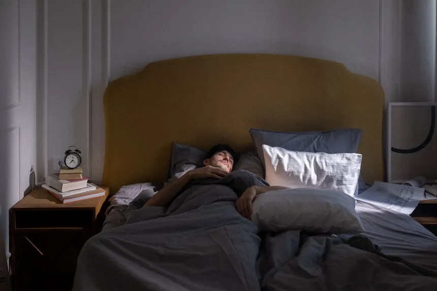 A man asleep in bed as early light comes through the window