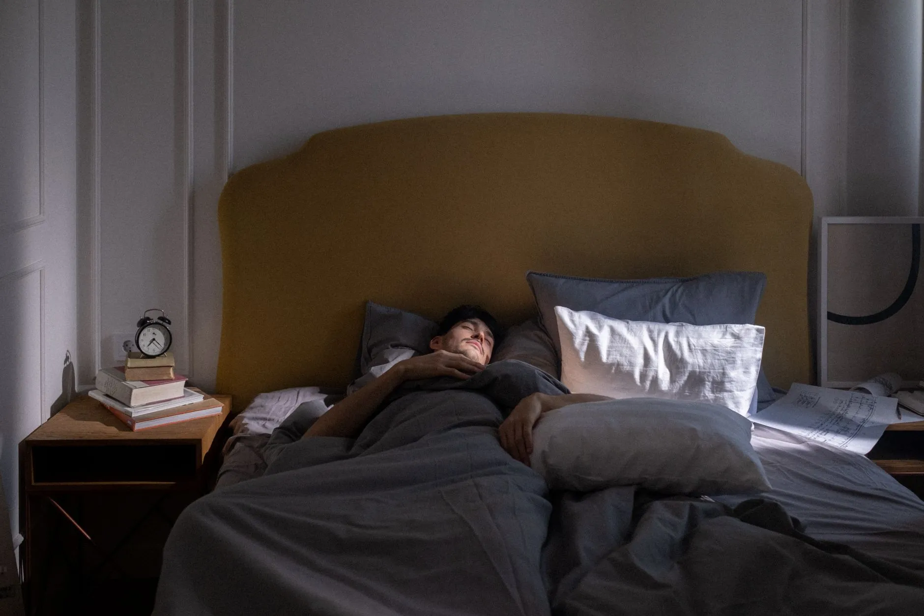 A man asleep in bed as early light comes through the window